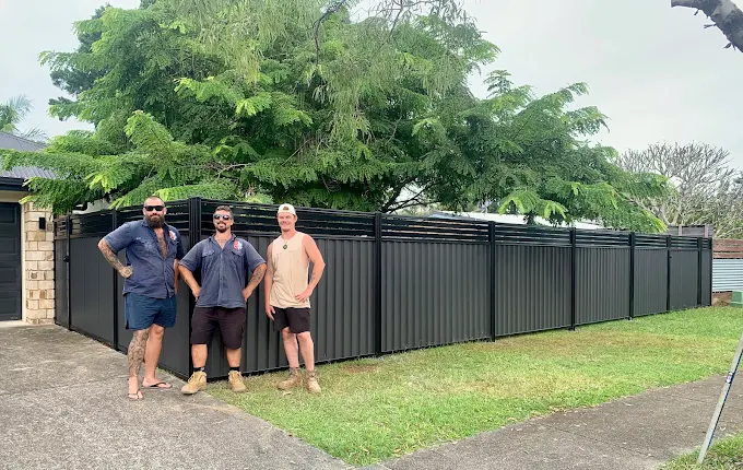 The GoPro Fencing team standing in front of a new black Colorbond fence with slat top