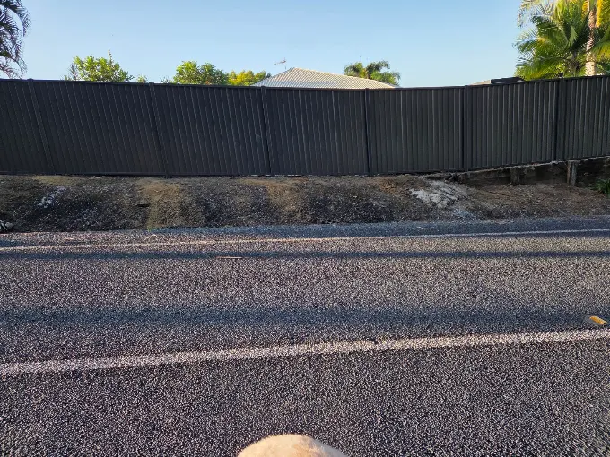 Black Colorbond fence installed along a sloping street frontage