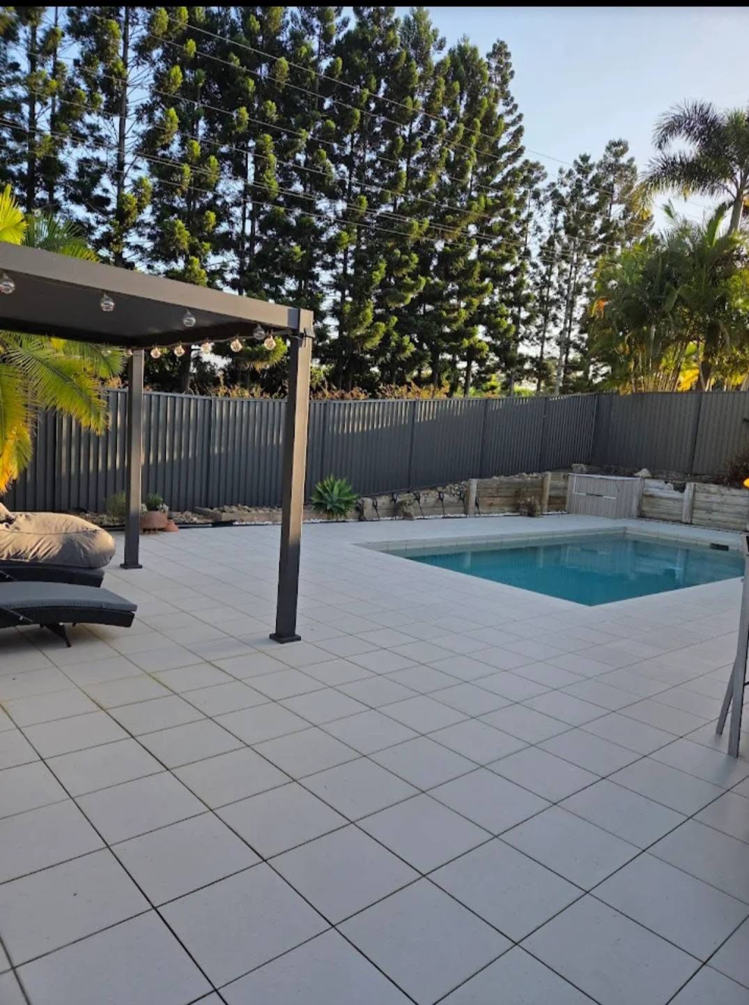 Grey Colorbond pool fence around a tiled pool with pergola on the Sunshine Coast