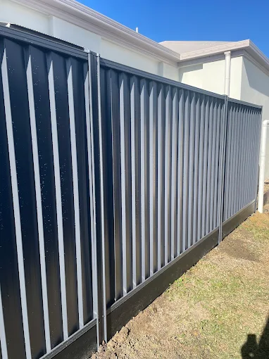 Dark grey Colorbond privacy fence with vertical slat detail beside a home