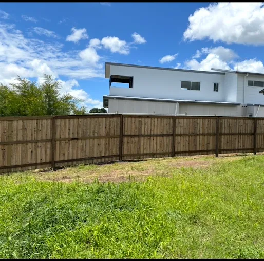 Long run of new timber paling fence in front of a modern white home