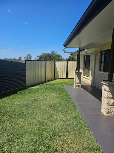 Cream Colorbond fence running the length of a sunny suburban front yard