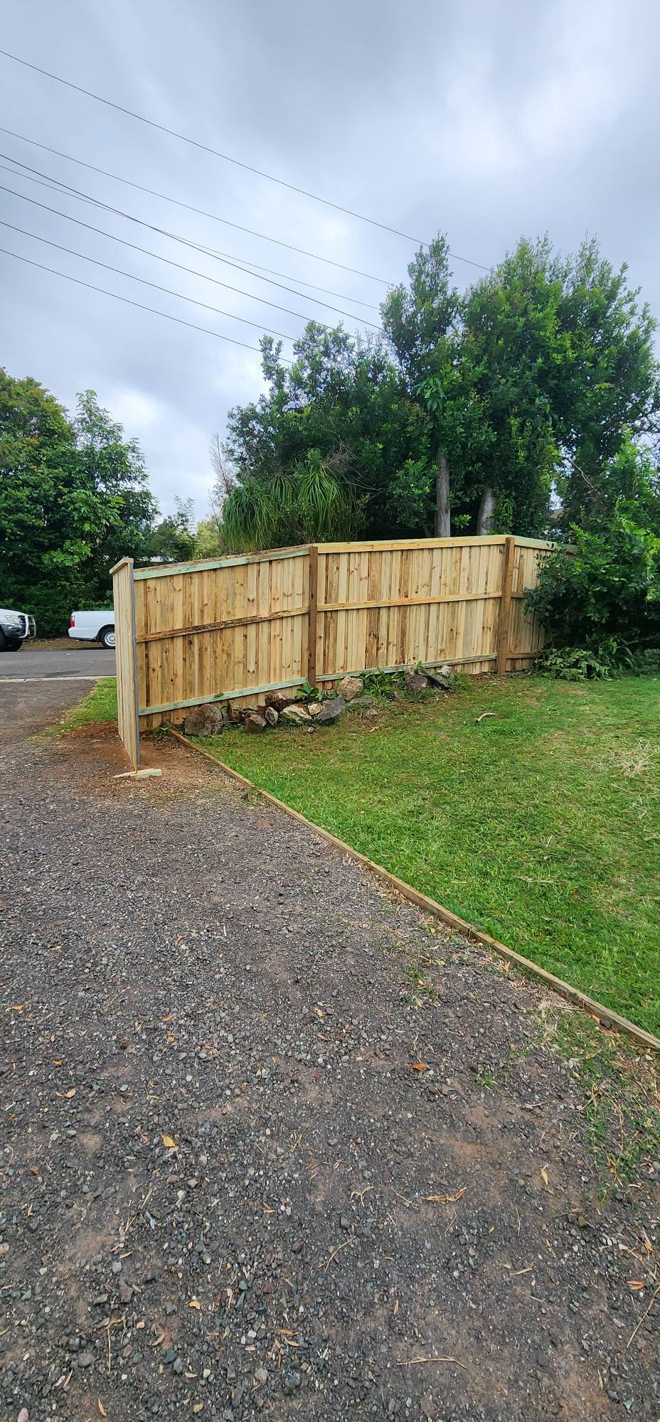 New treated pine paling fence built along a rural driveway